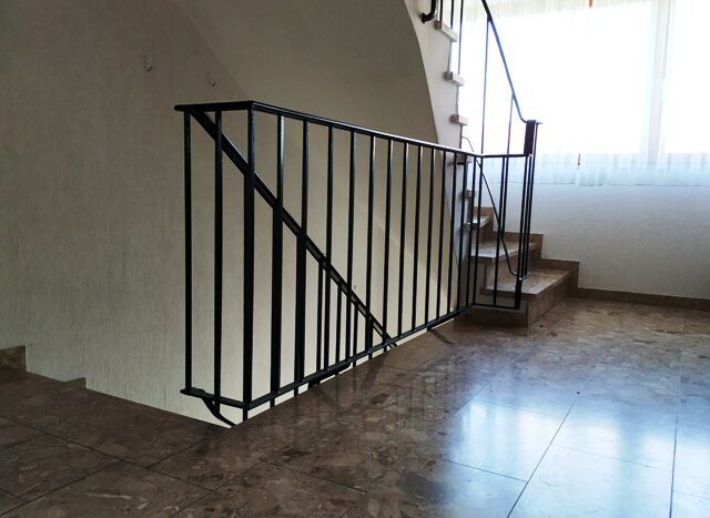 Treppenhaus mit Steinfußboden und Eisengeländer